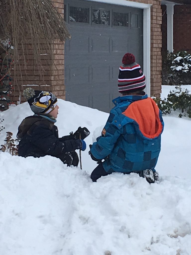 2 boys playing in the snow in the winter