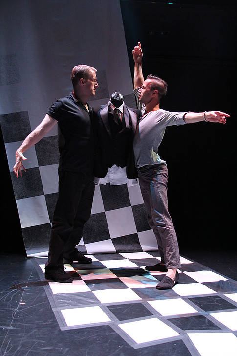 Two men in ballroom dancing positions, with a tuxedo jacket on a mannequin behind them.