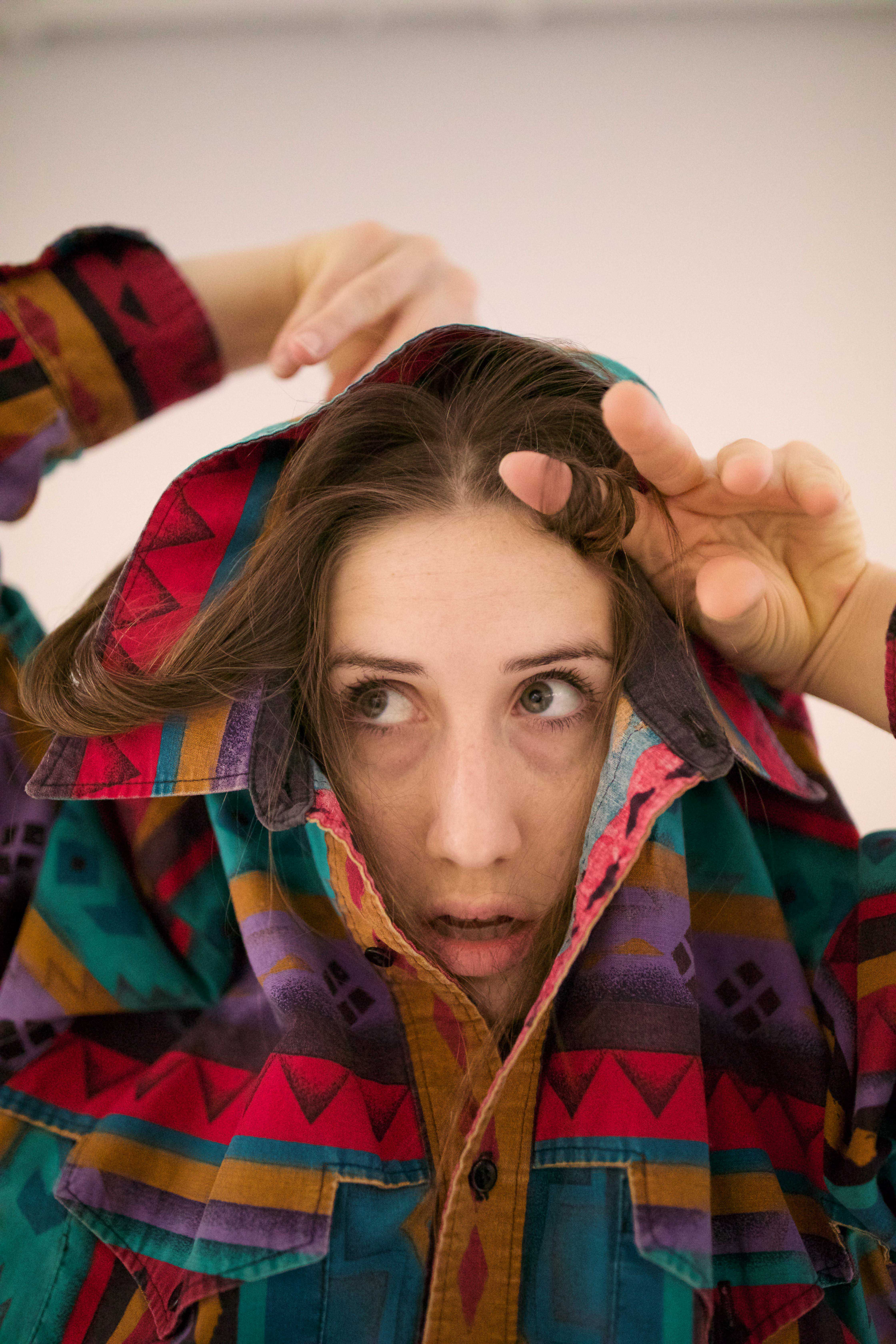 Woman disappearing into a colourful shirt, whose collar is pulled up behind her head