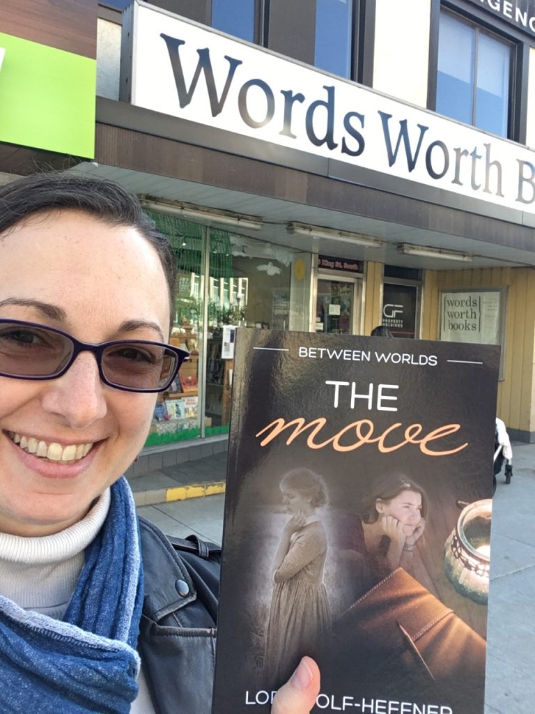 Canadian author Lori Wolf-Heffner holds a copy of "Between Worlds 1: The Move," the first in her young adult series about dance, in front of Words Worth Books in Waterloo