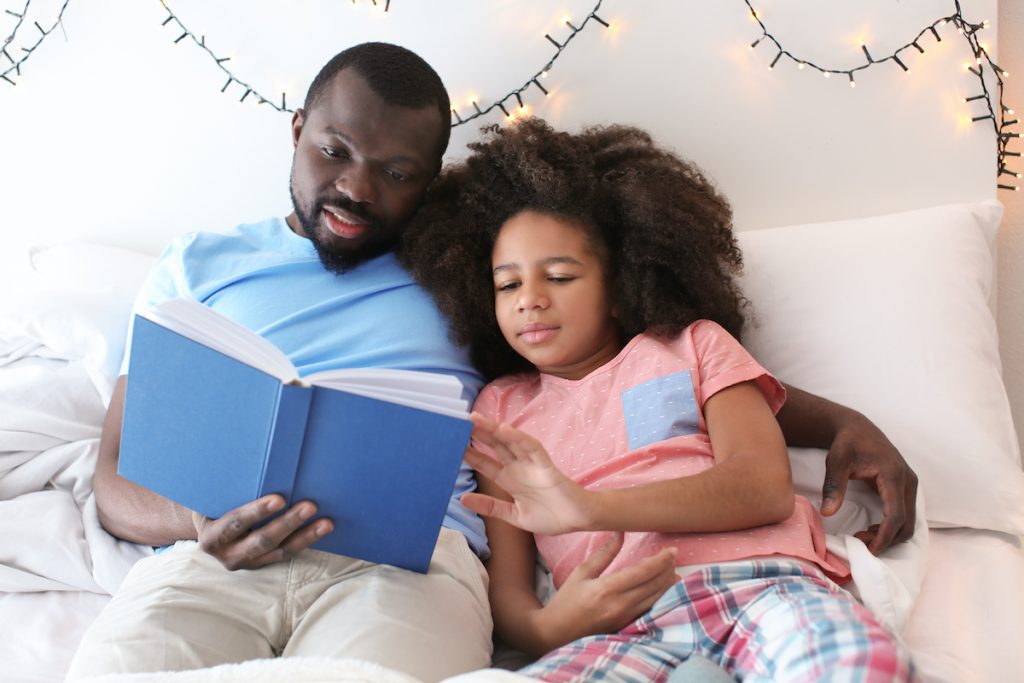 Father reading to his pre-teen daughter