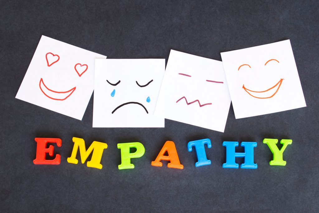 The word "empathy" spelled in colourful letters, with drawings of different facial expressions above