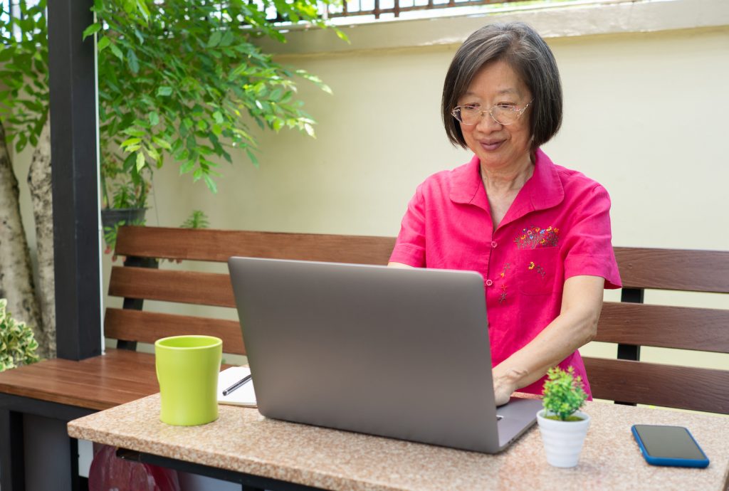 An Asian woman sitting at a computer, writing emails