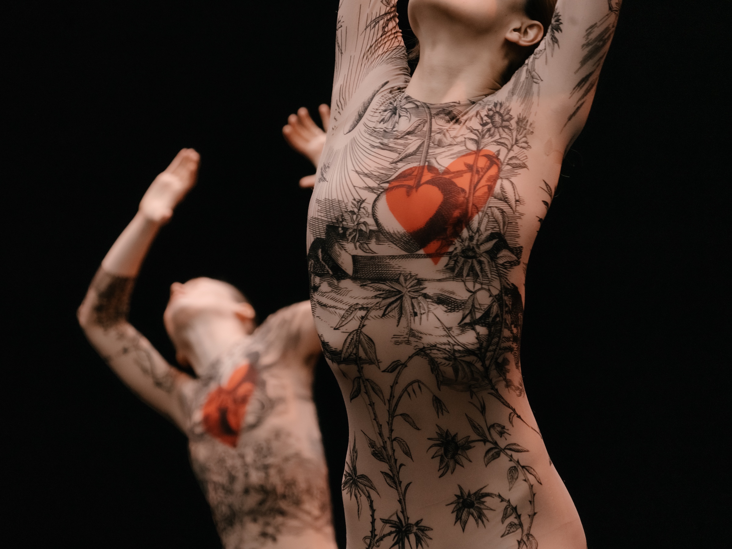 Dancers in costumes that look like body tattoos but with a red heart drawn where the heart is.