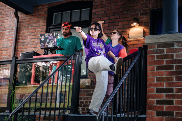 Three people showing some attitude as they groove on their porch.